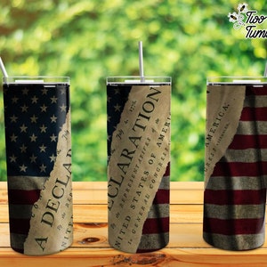 May include: Three stainless steel tumblers with a distressed American flag design. The tumblers have a white straw in each. The middle tumbler has a torn piece of paper with the text "Declaration of Independence" on it.