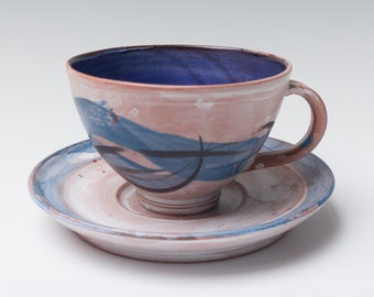 May include: A ceramic teacup and saucer set with a blue and brown abstract design. The cup has a blue interior and the saucer has a blue rim.