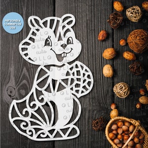 May include: A white digital cut file of a cartoon squirrel holding a nut. The file is for use with Cricut and Silhouette cutting machines. The image is on a dark wood background with nuts and fall decor.