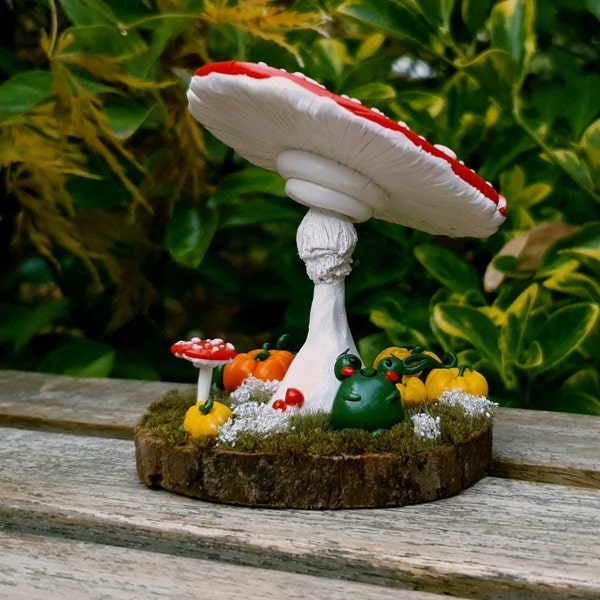 Décoration en pâte Fimo Petite grenouille sous un champignon reposant sur un rondin de bois