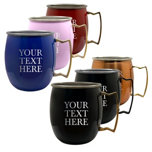 May include: Set of five copper mugs in different colors, including red, pink, blue, black, and copper. Each mug has a gold-colored handle and the text "YOUR TEXT HERE" engraved on the front.