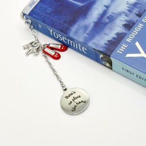May include: A silver bookmark with a chain, a red pair of shoes, and a small silver elephant charm. The bookmark has a round charm with the text "there's no place like home".