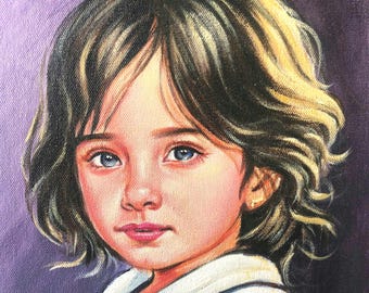 May include: A portrait of a young person with blue eyes and wavy brown hair. The subject is wearing a white collared shirt with a blue and pink accent. The background is a solid purple color.