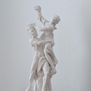 Könnte beinhalten: Weiße Marmorskulptur eines Mannes und einer Frau, die sich umarmen. Die Skulptur steht auf einem schwarzen Marmorsockel.