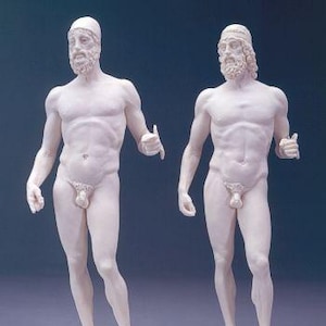 May include: Two white marble statues of nude men standing on black bases. The statues are of classical Greek style and are both wearing headbands. The statues are labeled with the numbers 10-1058-1012 and 10-1057-1012.