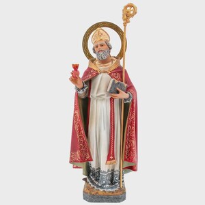 Op de afbeelding: Een religieus beeldje van een bebaarde figuur met een mijter en een rode mantel met gouden filigraanpatronen over een wit gewaad. De figuur houdt een klein rood hart in de ene hand, een boek in de andere en staat voor een gouden cirkelvormige halo.
