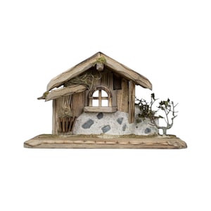 Può includere: Una casa in miniatura rustica in legno con un muro in pietra, una finestra ad arco e un tetto in legno stagionato. La casa è decorata con piccole piante e muschio, creando un'estetica naturale e affascinante.