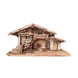 Può includere: Un chalet alpino in legno in miniatura dal design rustico. Lo chalet presenta un tetto spiovente, un piccolo balcone e una facciata in pietra. La struttura comprende una scala, una porta ed elementi decorativi.