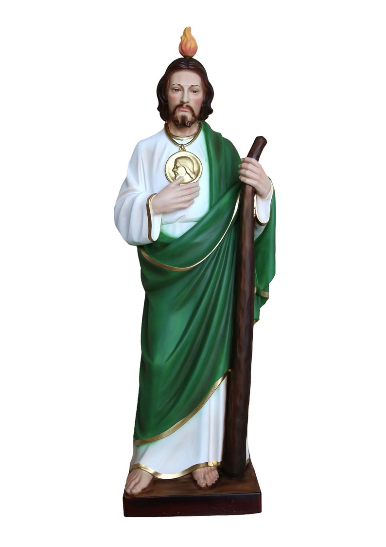 May include: A detailed statue of a religious figure, featuring a white robe with gold trim, a green cloak, and a wooden staff. The figure has a beard, a halo, and a medallion. The statue stands on a dark brown base.