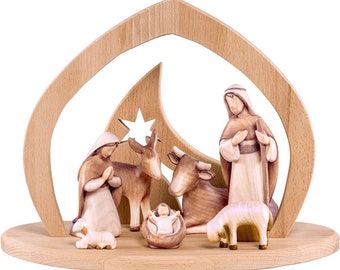 May include: A wooden nativity scene with a crescent moon and star cutout. The scene includes Mary, Joseph, baby Jesus, a cow, a donkey, and two sheep. The figures are made of painted wood and are in a natural wood tone.