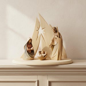 May include: A light-coloured wooden nativity set featuring carved figures of a person with hands clasped, a person holding a staff, and a small infant in a cradle. Behind the figures stands a tall, pointed wooden backdrop with a star cutout.