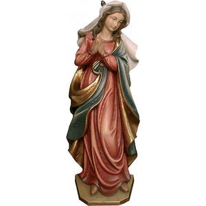 May include: A wooden statue of a woman in a long, flowing dress with her hands clasped in prayer. The statue features a red dress, a blue shawl, and gold accents. A white veil covers her head.