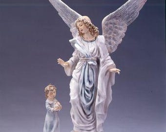 May include: A porcelain figurine of an angel with wings outstretched, holding a small child. The angel is wearing a white dress with blue accents and the child is wearing a blue dress. The figurine is on a wooden base.