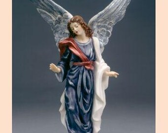 May include: A porcelain figurine of an angel with silver wings. The angel is wearing a blue robe with a red sash and a white shawl. The angel is standing on a cloud base.