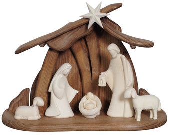 Op de afbeelding: Een houten kerststal met een bruine houten stal en witte figuren van Maria, Jozef en het kindje Jezus. Twee witte houten schapen staan aan weerszijden van de stal.
