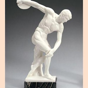 May include: White marble sculpture of a discus thrower in mid-throw, standing on a black marble base. The sculpture is a classic representation of athleticism and strength.