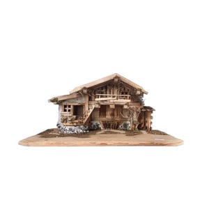 Può includere: Un chalet in legno in miniatura dal design rustico. La struttura a due piani presenta un balcone, travi in legno dettagliate e una finitura in legno naturale. La base è di colore marrone chiaro e il tetto è inclinato.
