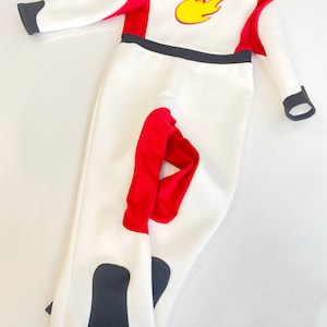 May include: White jumpsuit with red and black accents. The jumpsuit has a flame design on the chest.