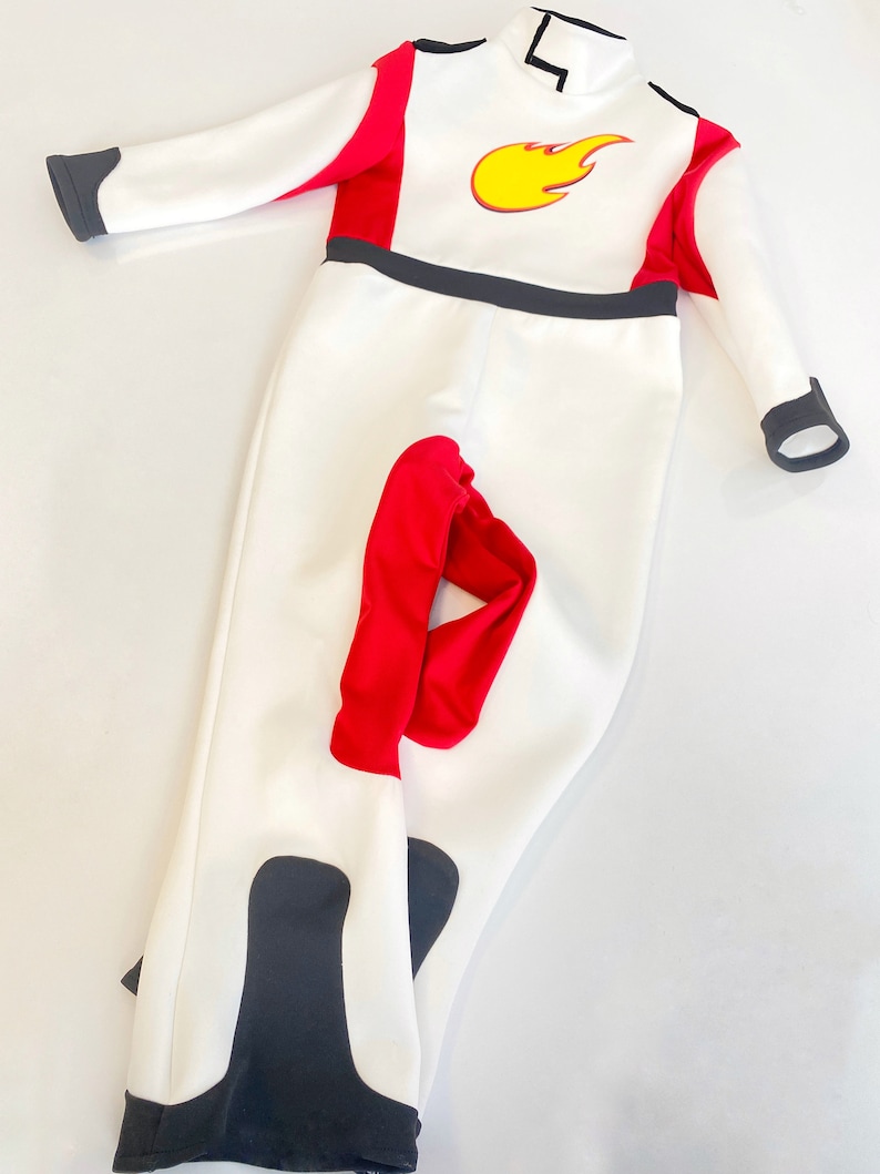 May include: White jumpsuit with red and black accents. The jumpsuit has a flame design on the chest.