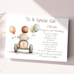 May include: A personalized birthday card for a son turning two years old. The card features a watercolor illustration of a boy riding a toy car with balloons and the text "To A Special Son Charlie On your 2nd Birthday Two years of laughter, two years of fun, Watching you grow, our little one. With each new moment, our hearts fill with pride, from tiny steps to big dreams in view, The world is brighter because of you! Love you to the moon and back Mummy & Daddy xx"