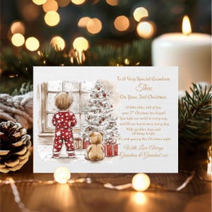 Peut inclure: Une carte de Noël avec une illustration à l'aquarelle d'un enfant en pyjama rouge regardant un sapin de Noël. La carte porte le texte "To A Very Special Grandson Theo On Your 2nd Christmas". Un ours en peluche et des cadeaux sont également présents.
