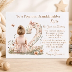 May include: A rectangular birthday card featuring a watercolor illustration of a child with blonde hair in a pink dress sitting next to a large floral number two. The text reads To A Precious Granddaughter Rosie On Your 2nd Birthday with a poem.