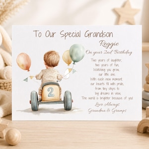 May include: A rectangular greeting card featuring a watercolor illustration of a child on a toy car with balloons. The text reads: To Our Special Grandson Reggie On your 2nd Birthday, followed by a poem and the signature Love Always Grandma & Gramps.