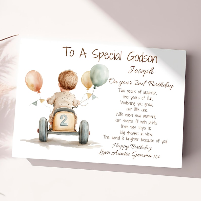 May include: A birthday card for a godson, featuring a watercolor illustration of a boy riding a toy car with balloons. The card reads "To A Special Godson Joseph On your 2nd Birthday Two years of laughter, two years of fun, Watching you grow, our little one. With each new moment, our hearts fill with pride, from tiny steps to big dreams in view, The world is brighter because of you! Happy Birthday Love Auntie Gemma xx"