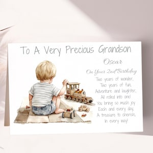 May include: A greeting card with a watercolor illustration of a young child playing with toy cars and a train. The text reads "To A Very Precious Grandson" and a birthday message. The card is light in color.