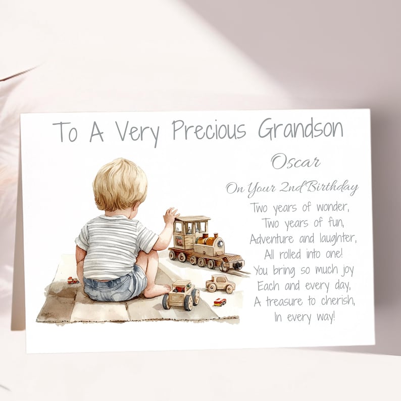 May include: A greeting card with a watercolor illustration of a young child playing with toy cars and a train. The text reads "To A Very Precious Grandson" and a birthday message. The card is light in color.