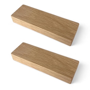 May include: Two rectangular wooden blocks with a light brown finish. The blocks are made of wood and have a natural grain pattern. The blocks are positioned on a white background.