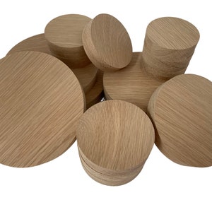 May include: A collection of various sized round wooden discs, stacked and arranged in a pile. The discs are made of light brown wood with a natural grain pattern.