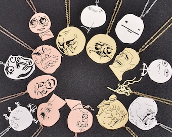 May include: A set of 14 gold and silver necklaces with different meme faces and expressions. The necklaces are on a black background.