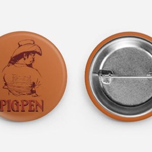 May include: A brown button with a drawing of a person wearing a cowboy hat and the text "PIG PEN" in red.