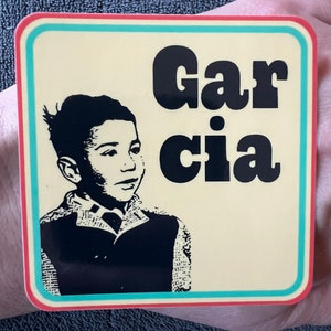 May include: Square sticker with a cream background, a teal border, and a red border. The sticker features a black and white illustration of a young person and the name "Garcia" in bold black letters.