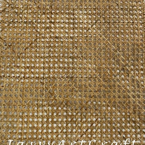 Puede incluir: Una lámina de tejido de mimbre tejido, también conocido como cannage, de color marrón natural. La lámina está hecha de finas tiras de mimbre tejidas juntas para crear un patrón de cuadrícula. La lámina se coloca plana sobre una superficie blanca.