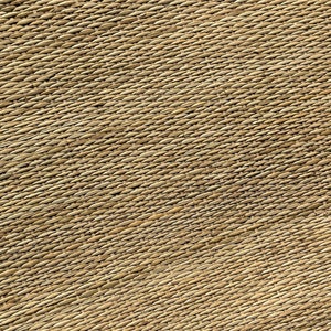 Pode incluir: Um close-up de um tapete tecido de fibra natural com um padr&atilde;o diagonal. O tapete &eacute; de cor castanho claro e tem uma textura &aacute;spera. O texto "Jassy Artcraft" &eacute; vis&iacute;vel no canto inferior direito da imagem.