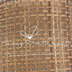 Puede incluir: Un trozo rectangular de material tejido en tonos marrones y beige. El patrón de tejido es apretado y uniforme, creando una superficie texturizada. El texto "Jassy Art Craft" está escrito en cursiva blanca en el centro del material.