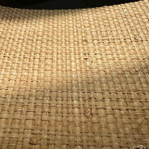 May include: Close-up of a woven wicker surface, showcasing a detailed pattern of interwoven strands in a natural beige hue. The texture is rough and organic, with subtle variations in color and weave density. The image is well-lit, highlighting the craftsmanship.