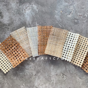 May include: Assortment of woven cane webbing samples in various natural tones, including light beige, medium brown, and dark brown. The samples are arranged in a fan shape, showcasing the different colors and textures of the material. The text "Jassy Art Craft" is visible.