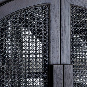 May include: A black wooden cabinet door featuring a central panel of woven cane webbing. The frame is constructed from dark stained wood with a visible grain texture, and the design includes a vertical handle integrated into the door edge.
