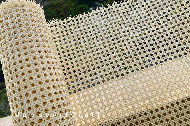May include: A roll of beige cane webbing, also known as caning, used for chair seats and backs. The webbing is woven in a diamond pattern and has a natural, rustic look. The text 'Jassy Art Craft' is visible on the roll.