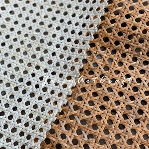 May include: Close-up of two woven cane panels, one white and one natural brown. The panels are made of thin strips of cane woven together in a diamond pattern. The white panel is on top of the brown panel.