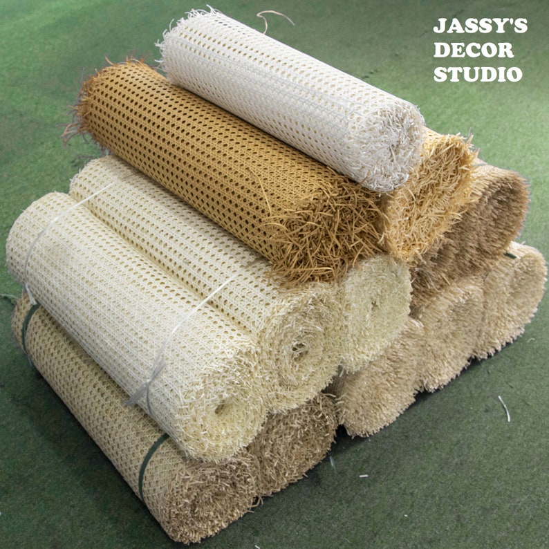 May include: A stack of rolled upholstery webbing in various colors, including white, beige, and brown. The webbing is a woven material used for supporting furniture cushions.