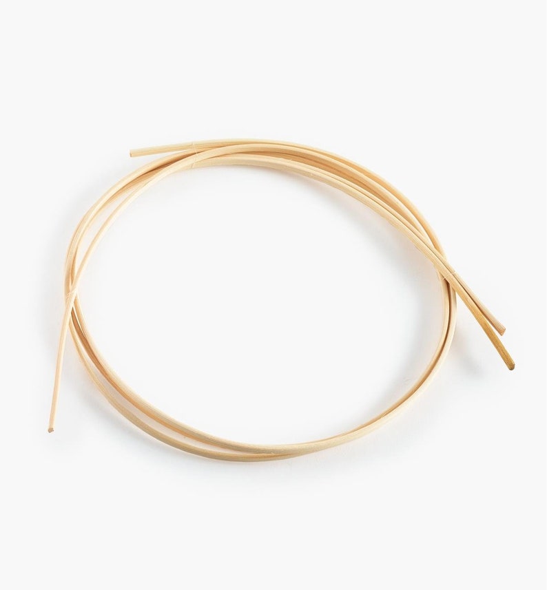 May include: A close-up of a bundle of natural, light brown, flexible, round, wooden dowels. The dowels are arranged in a circle.