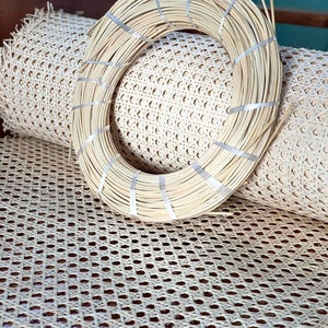 May include: A close-up of a roll of natural cane webbing, a woven material used for chair seats and other furniture projects. The webbing is beige in color and has a diamond pattern. A roll of natural cane is also visible in the image.