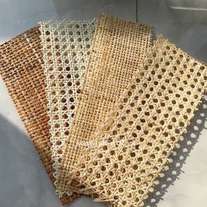 May include: Five rectangular pieces of woven cane webbing in varying shades of brown and beige. The webbing has a repeating pattern of small, evenly spaced holes, and is suitable for furniture repair or craft projects.