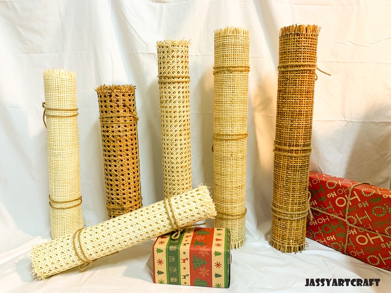 Puede incluir: Cinco rollos de tejido de ca&ntilde;a en varios tama&ntilde;os y colores, incluyendo natural, marr&oacute;n y blanco. Los rollos est&aacute;n atados con cuerda y est&aacute;n dispuestos sobre una superficie blanca.