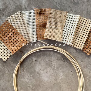 May include: Assortment of woven cane webbing samples in various shades of brown and white, arranged in a fan shape. A bundle of thin, light-colored wooden hoops is in the foreground. The text "Jassy Art Craft" is visible.