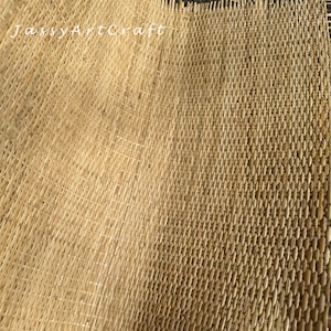 Pode incluir: Um close-up de um tapete tecido de fibra natural. O tapete &eacute; feito de um material marrom claro e tem um padr&atilde;o tecido. O tapete est&aacute; dobrado ao meio, mostrando o interior e o exterior da trama.